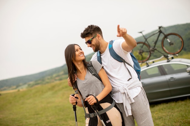 Couple of young hikers with backpacks starting a walk through the fields