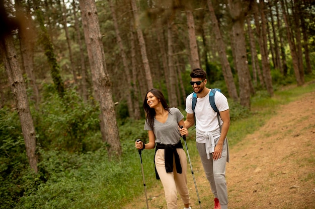 Couple of young hikers with backpacks walk through the forest