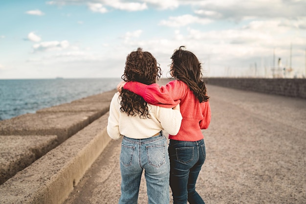 Couple of young woman walking seaside carefree concept of lesbian young girlfriends spending time thoughtless