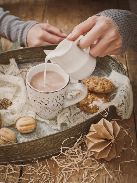 Coupnum up of hand pouring milk into cocoa