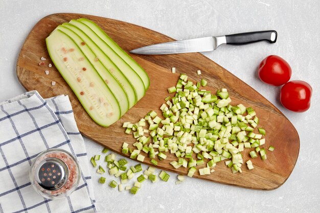 Courgette zucchini diced sliced on a wooden cutting board tomatoes garlic on a concrete light table