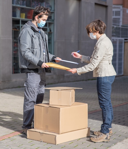 The courier delivers the order for the woman to sign, they keep the social distance