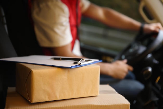 Courier driving delivery van focus on parcels and clipboard