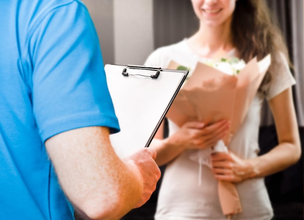 Courier with a document in his hands and a young woman with a bouquet , delivering flowers