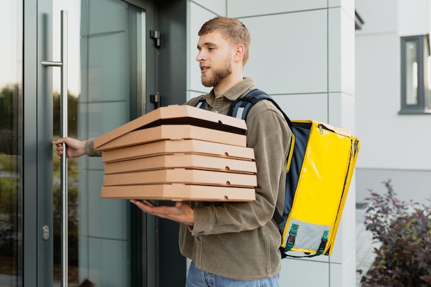 A courier with pizza boxes enters the entrance of a residential building to deliver an order Professional delivery in a big city