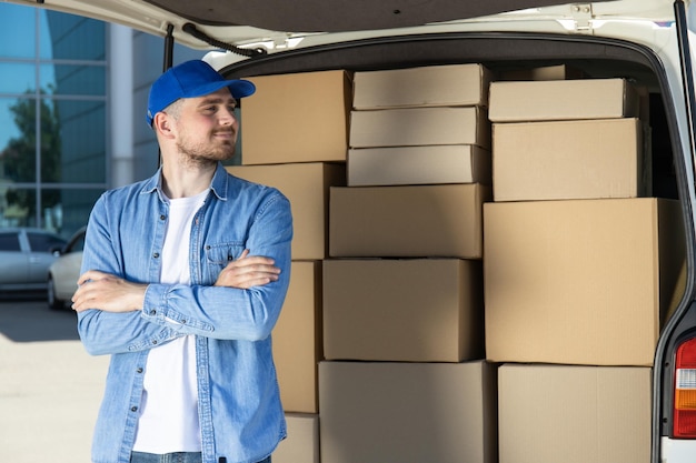 A courier with a tablet in his hands near a car with boxes