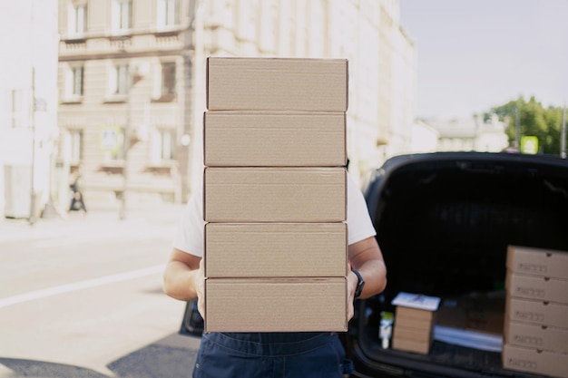 Photo a courier worker picks up packing boxes that are being placed in the car warehouse delivery