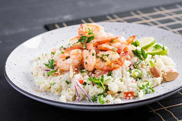 Couscous with roasted shrimps, tomatoes, red onions, almond nuts and parsley. Moroccan food with couscous and prawns.