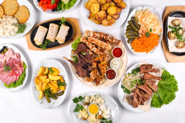 A covered table with many different dinner dishes. Lots of food on a white isolated background.