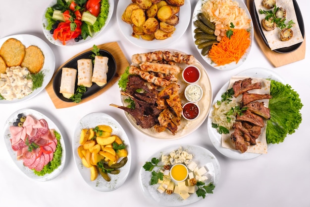 A covered table with many different dinner dishes. Lots of food on a white isolated background