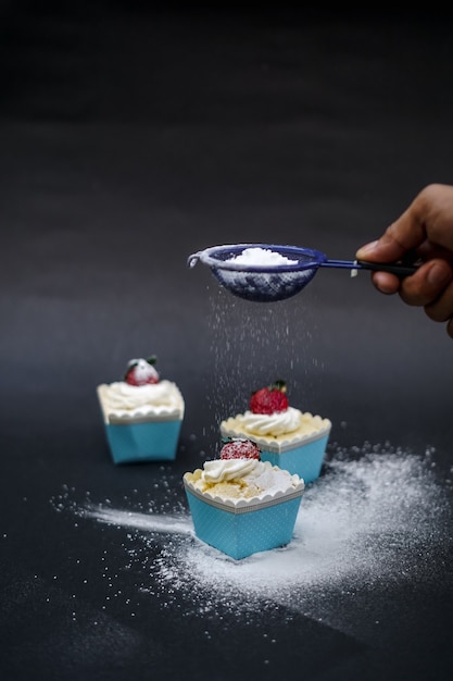 Covering the cupcakes with powdered sugar.