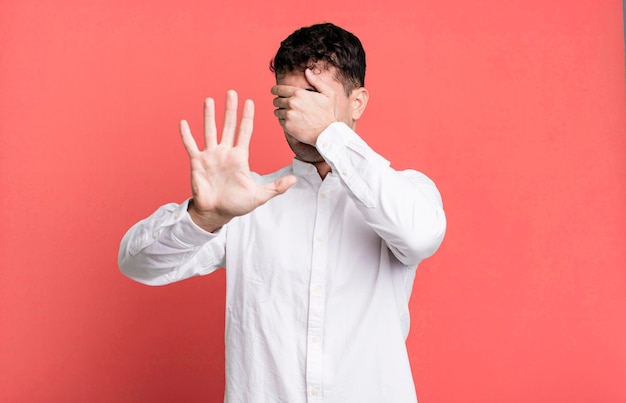 Covering face with hand and putting other hand up front to stop camera refusing photos or pictures