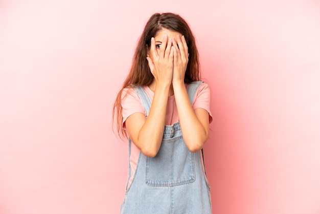 Covering face with hands peeking between fingers with surprised expression and looking to the side