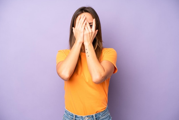 Covering face with hands peeking between fingers with surprised expression and looking to the side