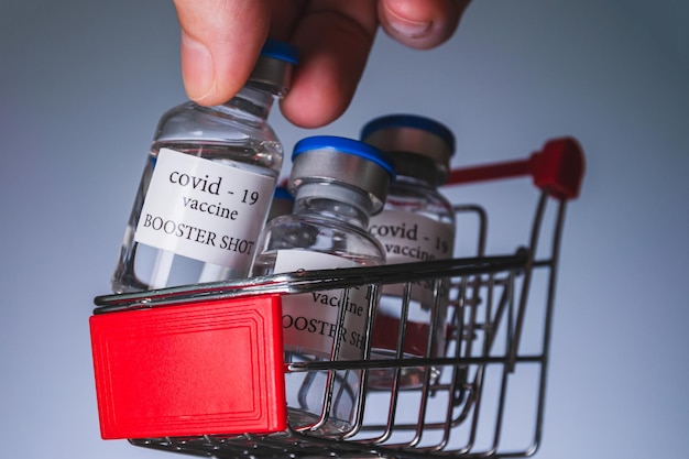 COVID-19 booster vaccine vials in shopping cart. Medicine and health care concept