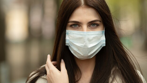 COVID-19 Pandemic Coronavirus Woman on city street wearing face mask protective for spreading of disease virus. Girl with protective mask on face against Coronavirus Disease 2019.