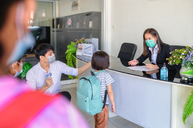 Covid-19 screening concept to students. The teacher greeted the students and screened for coronavirus infection, took body temperature, and took the student's fever in the morning before class.