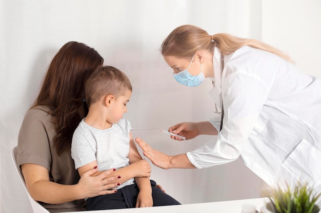 Covid 19 vaccine for children. Little caucasian boy getting vaccinated from Covid-19. A young female doctor holding syringe with coronavirus vaccine. Risk and infection control concept.