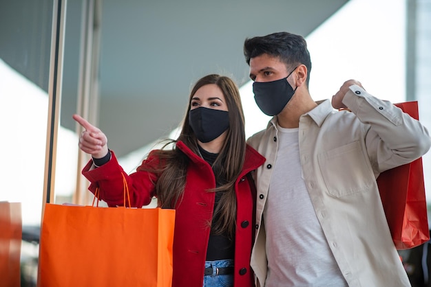 Covid and coronavirus shopping couple walking in a city while carrying shopping bags