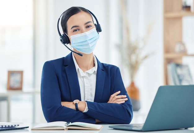 Covid telemarketing and woman with mask portrait at a corporate work building in the pandemic Help desk worker at table with medical face protection from coronavirus transmission with staff