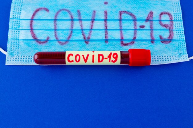 COVID19 Test tube with blood identified by the COVID19 coronavirus on classic blue background