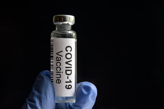 COVID19 vaccine on black background medication bottle for SARSCoV2 corona virus cure