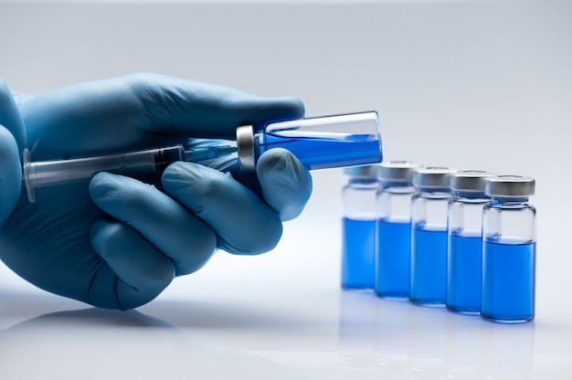 Covid19 Vaccine bottle with a blue liquid and taking the vaccine from it with a syringe.