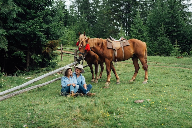 Cowboy and cowgirl in the mountains with their horses