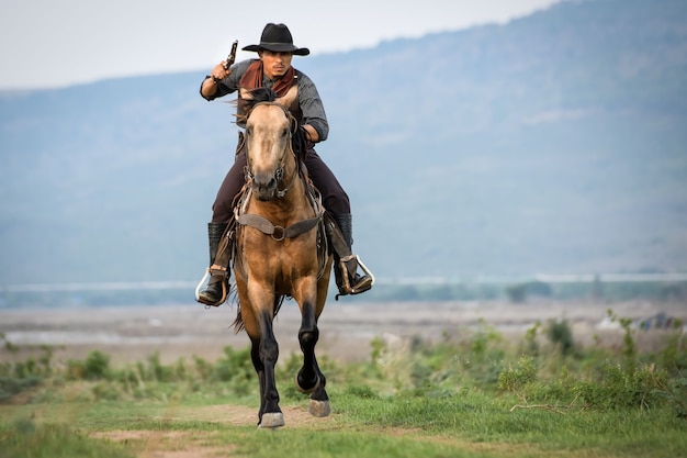 Cowboy man riding horse shooting