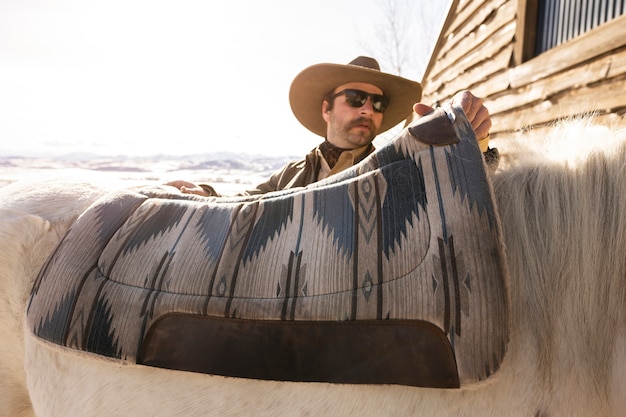 Cowboy putting saddle on horse