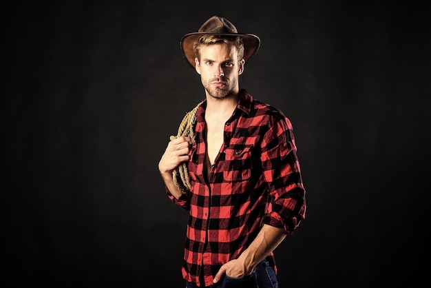 Cowboy wearing hat hold rope Lasso tool of American cowboy Still used on ranches to capture cattle or other livestock Western life Lassoing on prairie Man unshaven cowboy black background