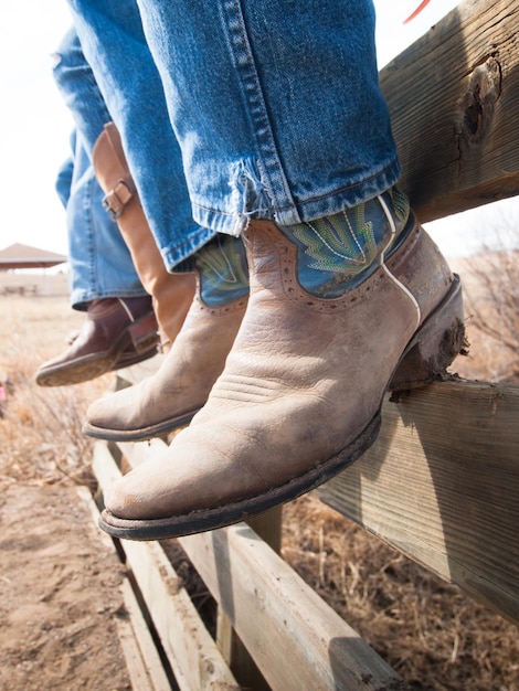 Cowboys and cowgirls sitting on wooden fence.