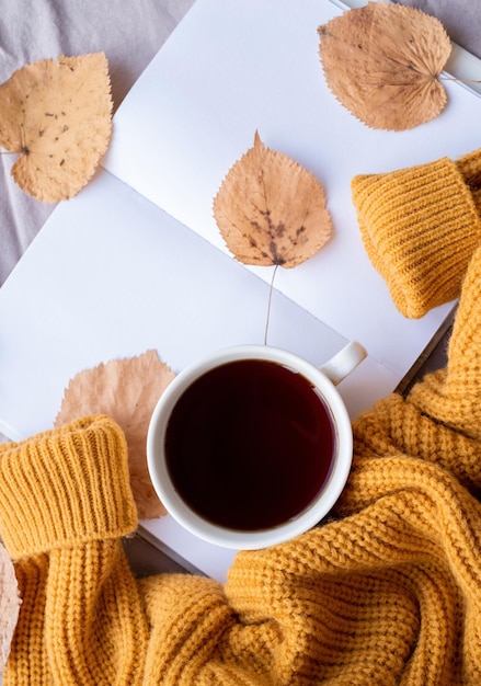 Cozy autumn composition sweater weather Tellow leaves hot tea and sweaters