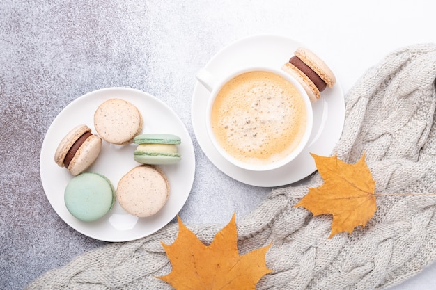 Cozy autumn composition with sweater, coffee, various macaron and yellow maple leaves on stone background. Flat lay, top view - Image