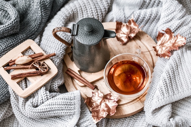 Cozy autumn morning breakfast in bed still life scene. Steaming cup of hot coffee, tea standing near window. Fall.