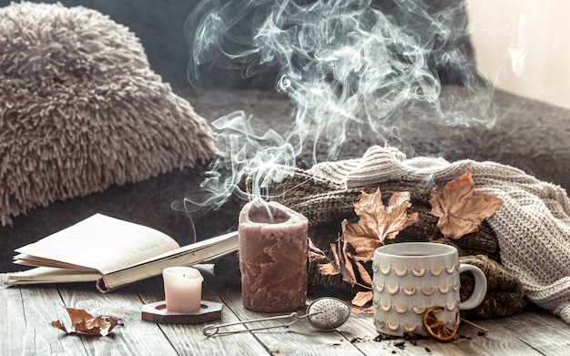 Cozy autumn morning breakfast in bed still life scene. Steaming cup of hot coffee, tea standing near window. Fall.