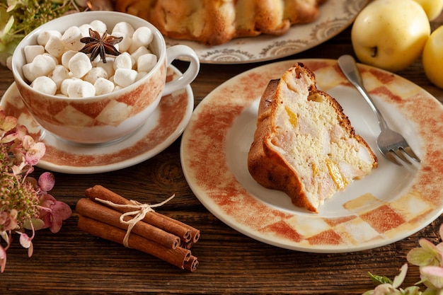 Cozy autumn still life with warm homemade biscuit apple pie and hot drink with marshmallow