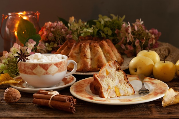 Cozy autumn still life with warm homemade biscuit apple pie and hot drink with marshmallow