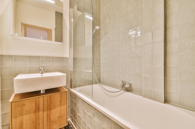 A cozy bathroom with a ceramic sink and a bathtub with a glazed shower in a modern house