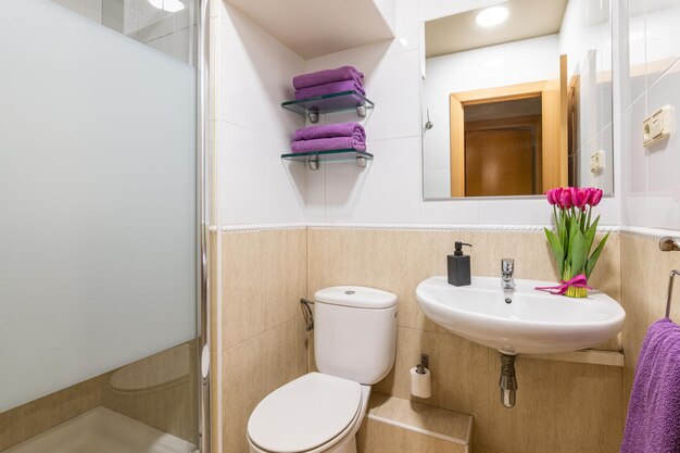 Cozy bathroom with toilet sink and mirror with towels and flowers in a hotel room while traveling