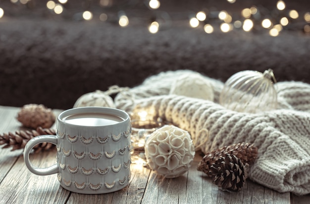 Cozy Christmas background with a beautiful cup and decor details on a blurred background with bokeh.