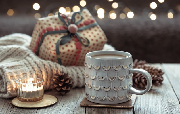 Cozy Christmas composition with a cup and festive decor details on a blurred dark background with bokeh.