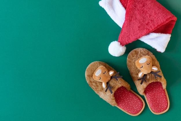 Cozy Christmas slippers on modern green background top view