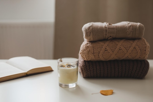 Cozy comfortable hygge home atmosphere and still life with a cup candle book and sweaters