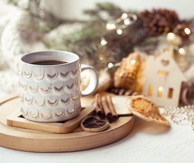 Cozy composition with a Christmas cup with a hot drink and cinnamon. Home winter coziness concept.