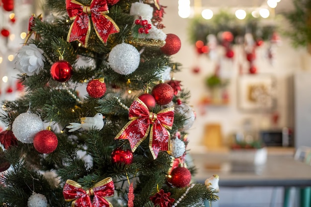 Cozy decorated christmas tree with red colored decor in hone interior close up