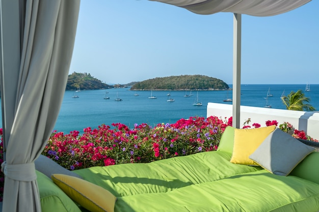 Cozy green sofa with pillows on site with views of the sea and yachts