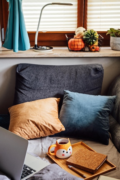 Cozy home autumn warm mood laptop notebook and cup of tea at tray on blanket in bed in the interior