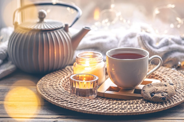 Cozy home composition with a cup of tea candles and a teapot