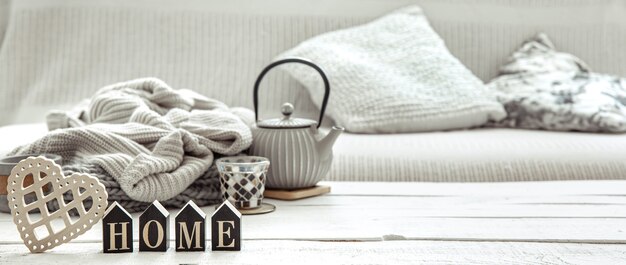 Photo cozy home composition with a teapot, knitted items and scandinavian decor details. concept of home comfort and modern style.